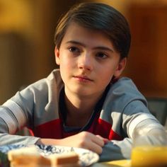 a young boy sitting at a table with food