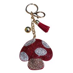 a red mushroom keychain with white dots on it and a tassel hanging from the front