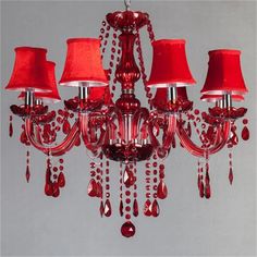 a red chandelier hanging from a ceiling with three lamps on each side and two shades of red