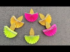 four different colored paper fan shaped objects on a table with gold and pink glitters