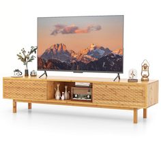 a flat screen tv sitting on top of a wooden entertainment center next to a vase