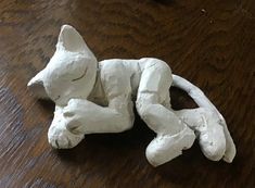 a white cat sculpture laying on top of a wooden table