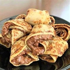 chocolate covered crepes are on a black plate