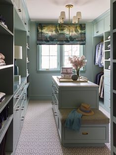 a walk - in closet with blue walls and drawers, white counter tops, and green cabinets