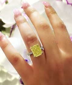 a woman's hand with a yellow and white diamond ring on top of it