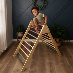 a young boy climbing up the side of a wooden ladder in front of a blue wall