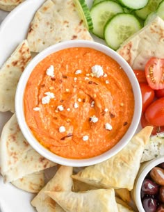 a plate with pita bread, olives, cucumber and tomato dip