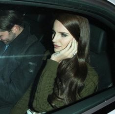 a woman sitting in the passenger seat of a car next to a man