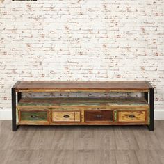 an old wooden table with drawers in front of a white brick wall and wood flooring