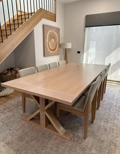 a large wooden table sitting in the middle of a living room next to a stair case