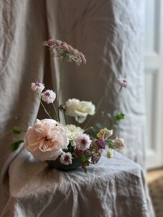 a vase filled with flowers sitting on top of a white tablecloth covered chair next to a window