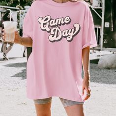 Make a statement with our retro game day t-shirt! Made with high-quality, comfortable fabric, this shirt is ideal for lounging on game day or heading out with friends. Get ready to turn heads with this fun and trendy addition to your wardrobe. Comfort Colors Garment Dyed 1717 Unisex Short Sleeve T-Shirt Relaxed fit, please check the size chart in photos to ensure the correct size.  100% Ring Spun Cotton Pre-Shrunk Fabric for size retention Care Instructions:  Machine wash cold inside out, Tumble Pink Crew Neck T-shirt For Game Day, Retro Game Day T-shirt With Screen Print, Retro Game Day T-shirt With Team Name, Retro Team Name T-shirt For Game Day, Retro Screen Print Tops For Game Day, Game Day Crew Neck Shirt With Text Print, Retro Letter Print T-shirt For Game Day, Graphic Tee Crew Neck Shirt For Game Day, Pink Letter Print Tops For Game Day