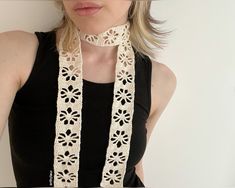 a woman wearing a white crochet necklace and black tank top with her hands in her pockets