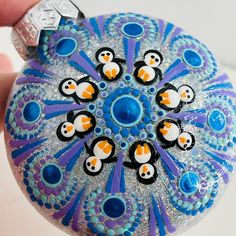 a hand holding a glass ornament with penguins painted on it's side