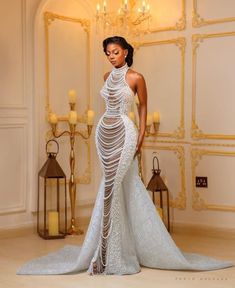 a woman in a white dress standing next to a chandelier