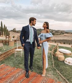 a man in a suit and tie standing next to a woman wearing a blue dress