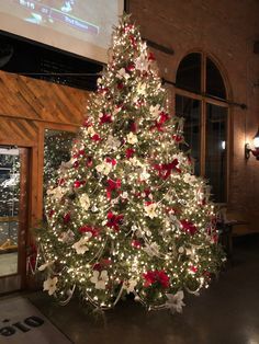 a decorated christmas tree in the middle of a room with a projector screen behind it