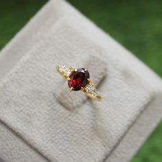 a red and white diamond ring sitting on top of a cloth covered napkin in the grass