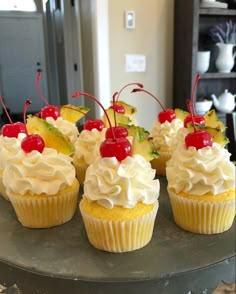 several cupcakes with cherries and pineapple toppings on a cake platter