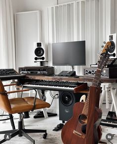 an acoustic guitar sitting in front of a keyboard and monitor