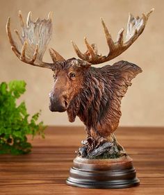 a statue of a moose with large antlers on it's head sitting on a table