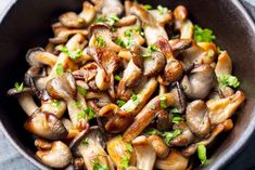 a bowl filled with mushrooms and parsley on top of a table