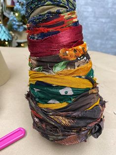 a stack of colorful scarves sitting on top of a table next to a pink pen