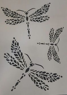 three black and white drawings of dragonflys on a sheet of paper with leaves