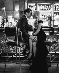 a man and woman sitting at a bar with their feet on each other's legs