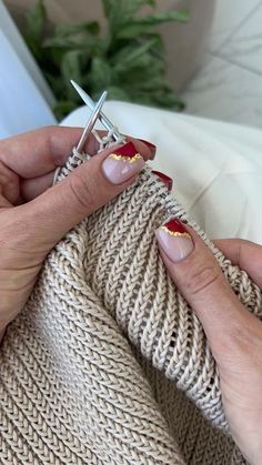 a woman with red and gold nail polish holding a pair of scissors