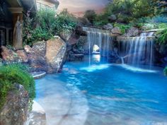 a pool with waterfall in the middle surrounded by greenery