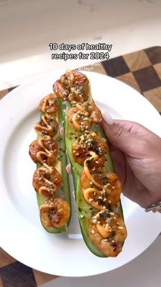 a person is holding up a long green vegetable on a plate with other food items