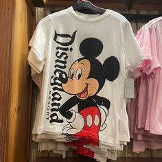 a mickey mouse t - shirt is hanging on a rack in a store with other shirts