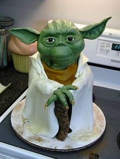 a cake made to look like yoda holding a piece of food in his hand