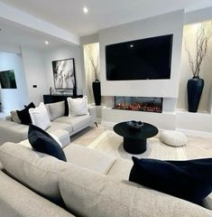 a modern living room with white couches and black table in front of the fireplace