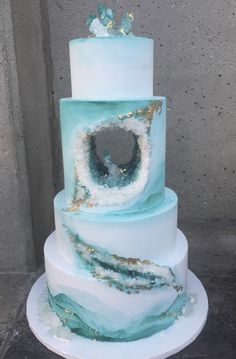 a three tiered blue and white cake with an eye on it's side