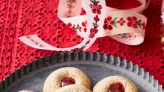 some sugary cookies are on a plate next to a glass of wine and ribbon