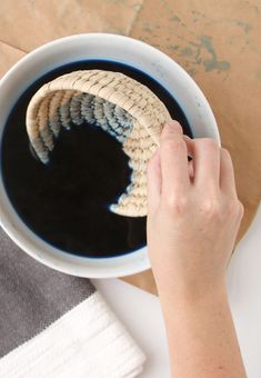 a person is holding a basket over a cup of black coffee in front of a brown paper bag