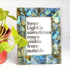 a photo frame sitting next to a potted plant with a quote on it that reads inner light is sometimes more visible from outside