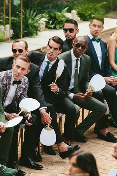 a group of men sitting next to each other holding frisbees in their hands