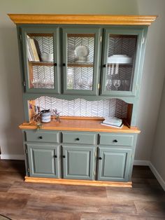 a green china cabinet with glass doors and drawers