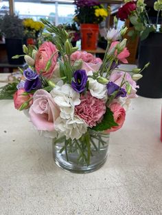 a vase filled with pink, white and purple flowers sitting on top of a table