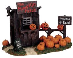 pumpkins are sitting in front of a wooden building with a sign that says the pumpkin patch