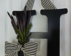 the letter h is decorated with black and white striped ribbon, as well as purple flowers