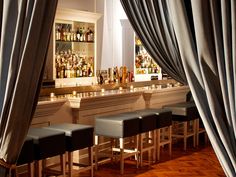 an empty bar with several stools in front of it and curtains hanging over the bar