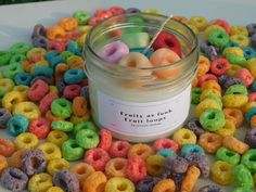 a jar filled with lots of colorful cereals on top of a white tablecloth