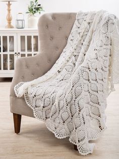 a white crocheted blanket sitting on top of a chair in a living room