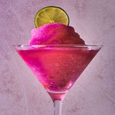 a pink drink with a slice of lime on the rim and purple sugar in it