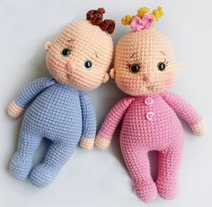 two crocheted dolls sitting next to each other on a white surface with one holding the head of another doll