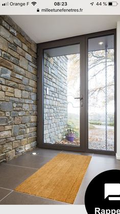 a door is open in front of a brick wall with glass doors and a rug on the floor